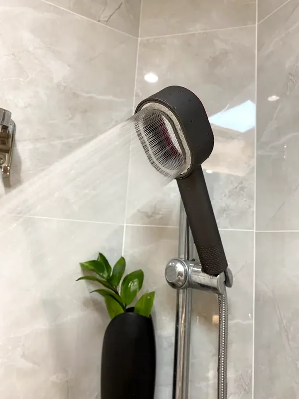 Närbild av ett duschhuvud med vattenstrålar, monterat i ett stilrent badrum. Vattenkvaliteten kan optimeras med ett system för Omvänd Osmos, vilket ger renare och hälsosammare duschar.